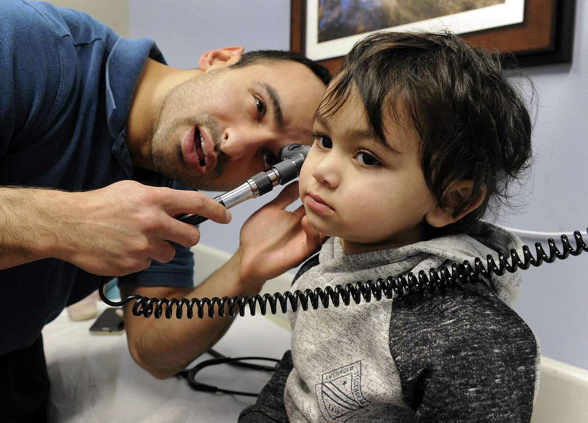 Physician's Assistant Haig Dodakian examines Jayce Mejias, 3, Thursday, at AFC Urgent Care in Danbury. Jayce has been complaining of a sore throat and has a difficult time sleeping.
