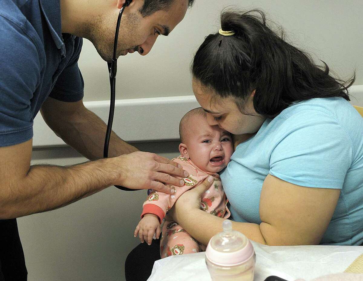 Physician's Assistant Haig Dodakian examines five-month-old Catalena Mejias, held by her aunt Ciomara Perez, at AFC Urgent Care on Newtown Road in Danbury, Thursday, Feb. 1, 2018. The baby is suffering from a variety of cold-like symtoms and is being tested for the flu.