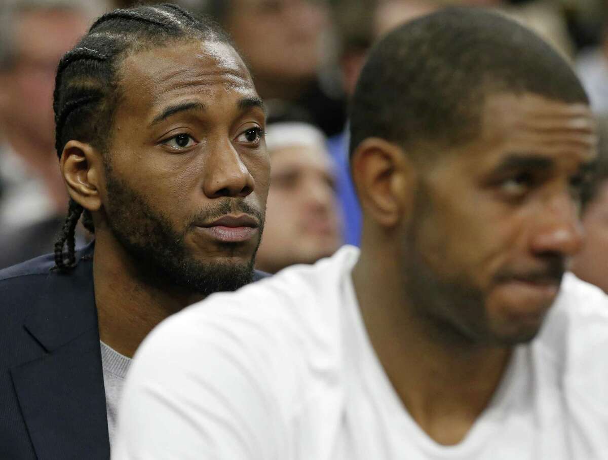 FILE: Kawhi Leonard and LaMarcus Aldridge watch the Spurs against the Houston Rockets on Feb. 1, 2018. The Spurs forward remains in New York to rehab the quad injury as his team continues their first-round playoff series with the Warriors.