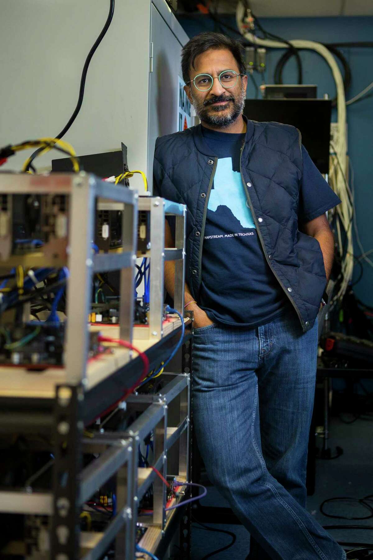Snapstream CEO Rakesh Agrawal, Wednesday, Jan. 24, 2018, in Houston. Agrawal's company is building cryptocurrency mining rigs (left) that use high powered video cards.