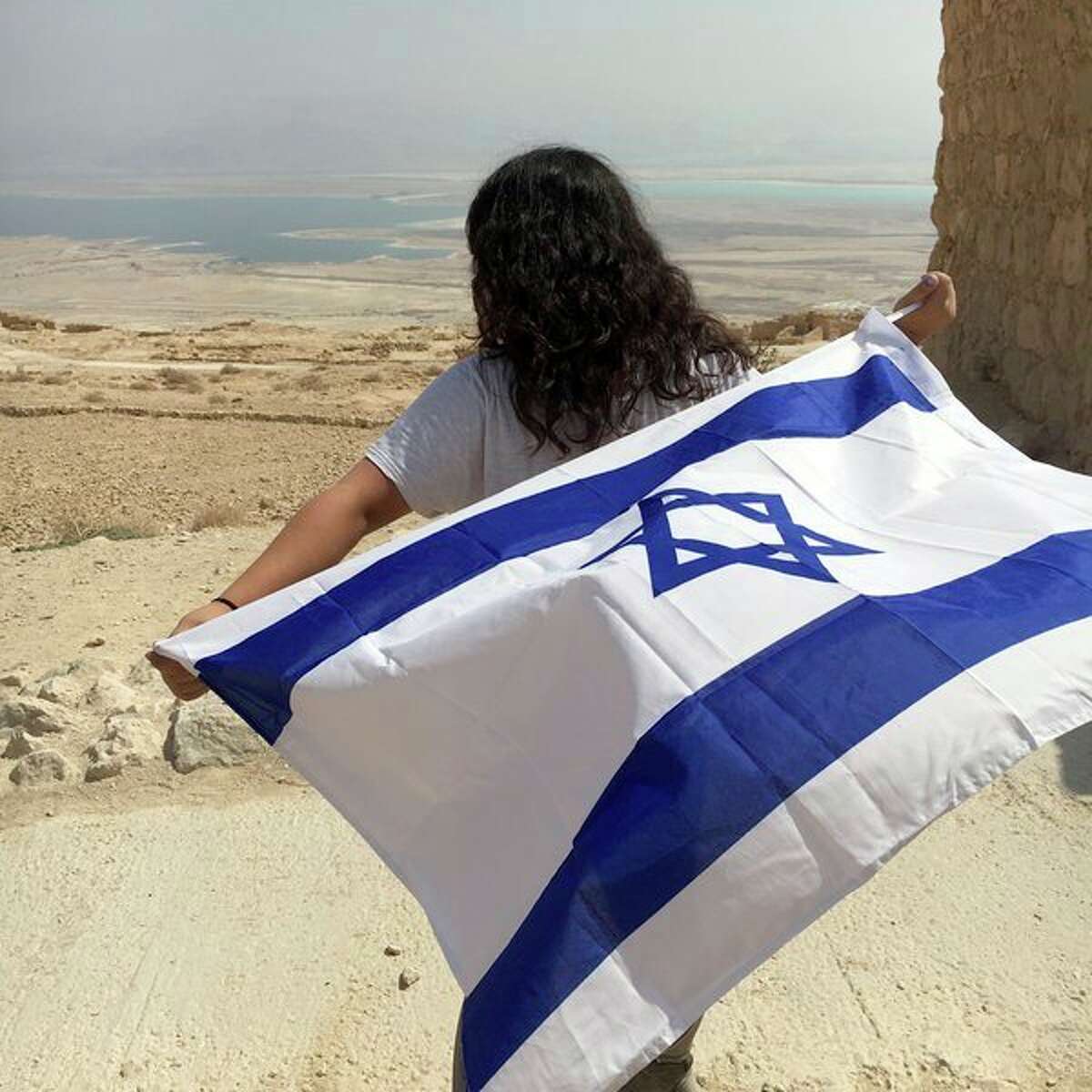 Rachel Kessler, 17, holds the Jerusalem flag while looking out toward the open land in Israel. (Submitted Photo)