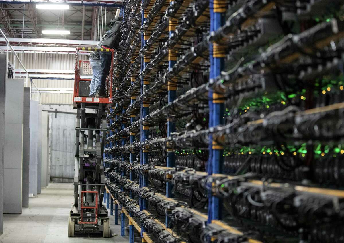 An employee inspects mining machines at the Bitfarms cryptocurrency farming facility in Farnham, Quebec, Canada, on Wednesday, Jan. 24, 2018.