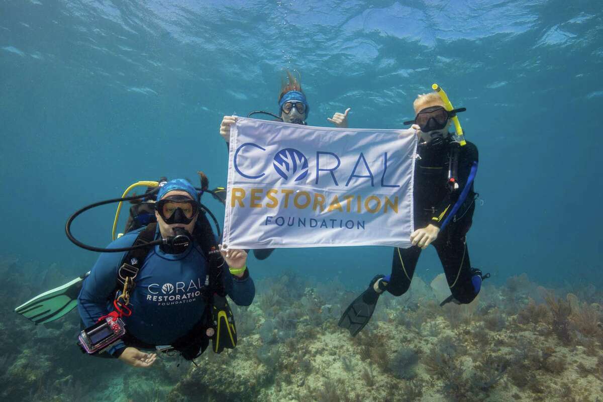 Henry Hittle (right) holds a banner with Coral Restoration Foundation staff members Jessica Levy (left) and Roxanne Boonstra (middle) during his last trip to volunteer with them in Key Largo last week, fundraising and educating his classmates as well.