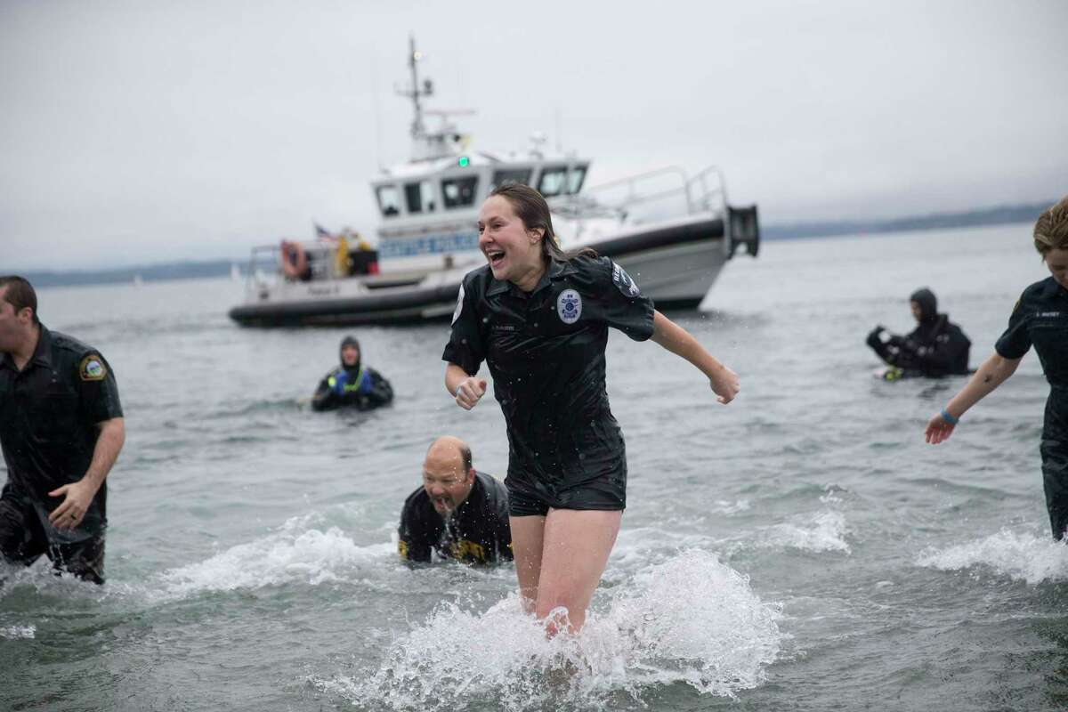 The "Blue Orphans" police fundraising team reacts to the cold water during the Washington Special Olympic Polar Plunge at Golden Gardens on Saturday, Feb. 3, 2018.