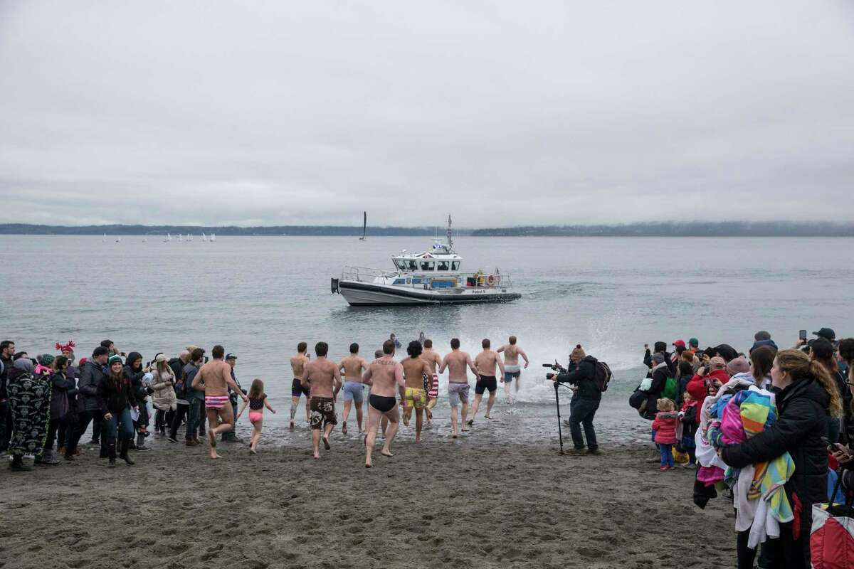 The Seattle Seawolves rugby team darts towards the water during the Washington Special Olympic Polar Plunge at Golden Gardens on Saturday, Feb. 3, 2018.