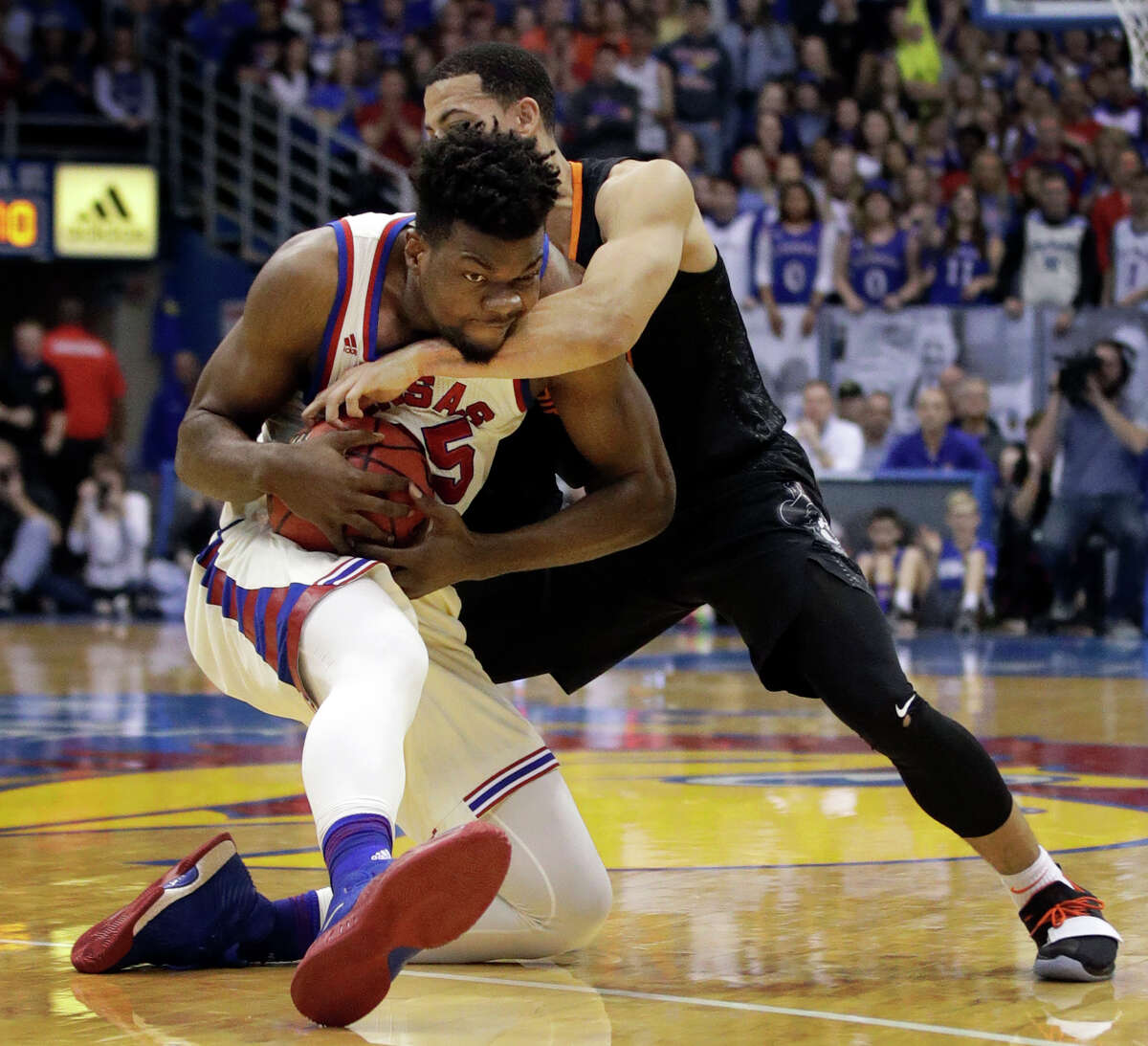 Kansas center Udoka Azubuike, left, is tied up by Oklahoma State guard Kendall Smith in the second half of Saturday's game at Lawrence, Kan. The Cowboys upset the No. 7 Jayhawks 84-79.
