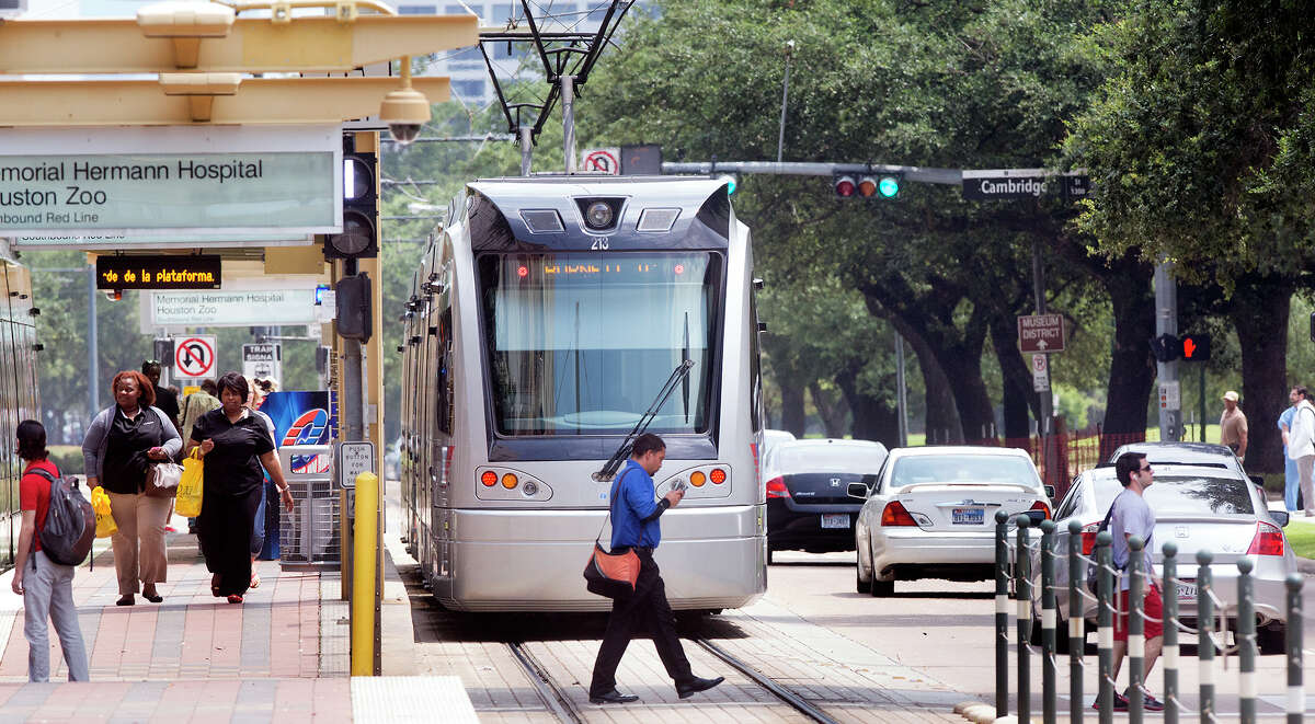 A METRO rail makes its way along the track as a group of pedestrians cross Fannin Street in the Medical Center, Thursday, July 24, 2014, in Houston.