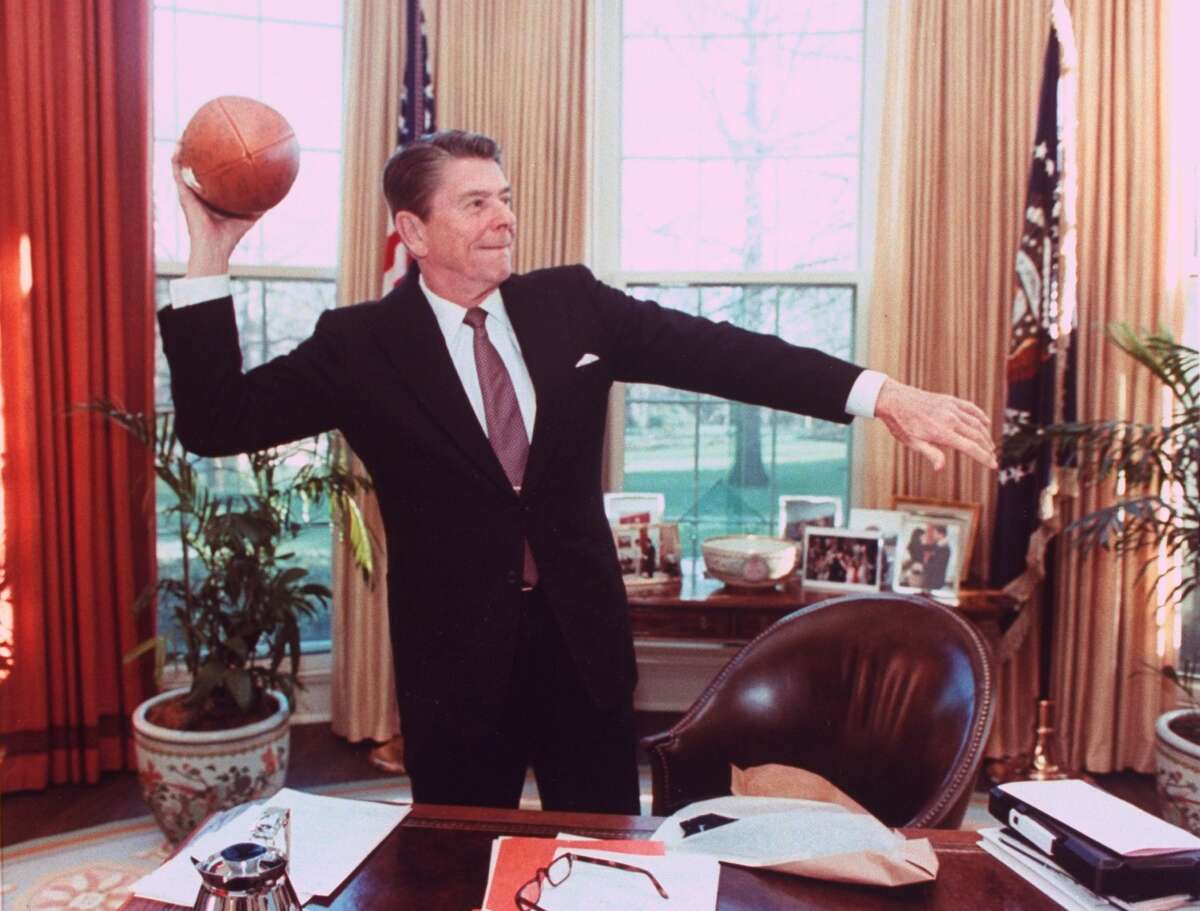 罗纳德·里根总统在椭圆形办公室的桌子上扔足球。