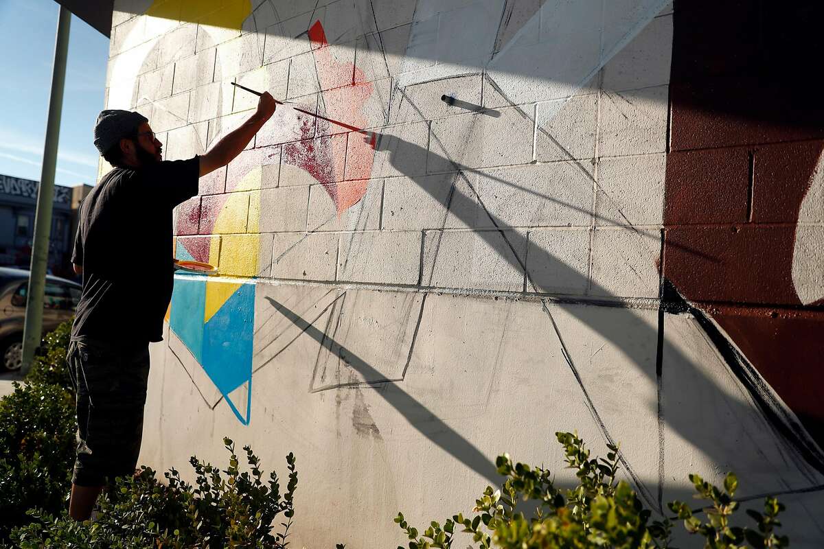 Muralist Max Martilla paints a mural on East Oakland Youth Development Center as before Covered California unveils it in Oakland, Calif., on Tuesday, November 7, 2017.