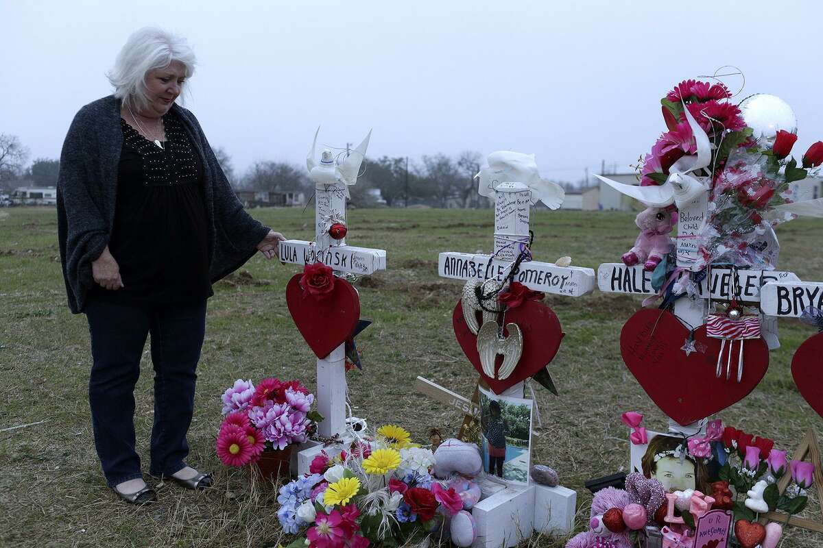Wearing her mother's sweater, Michelle Shields touches the memorial cross for her mother, Lula Woicinski White, next to First Baptist Church of Sutherland Springs on Tuesday, Feb. 6, 2018.