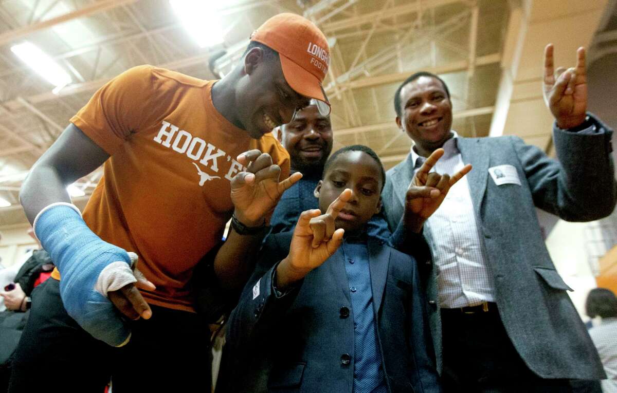 Oak Ridge's Joseph Ossai, left, helps his younger brother Chidera figure out the 'Hook 'em Horns' hand sign during a National Signing Day ceremony at Oak Ridge High School, Wednesday, Feb. 7, 2018. The defensive end signed to play football for the University of Texas.