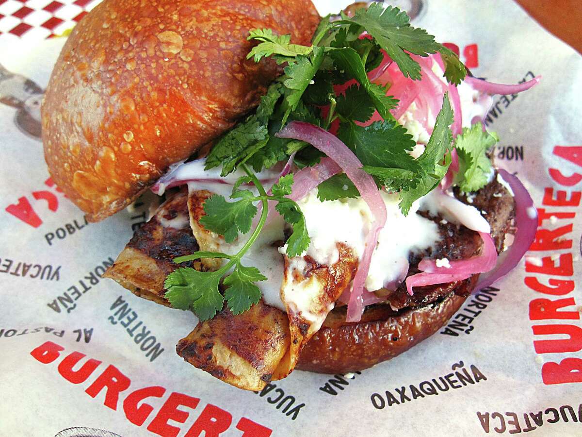 An enchilada burger with a beef patty, chile ancho, corn tortillas, queso fresco, crema, pickled red onions and cilantro from Burgerteca.