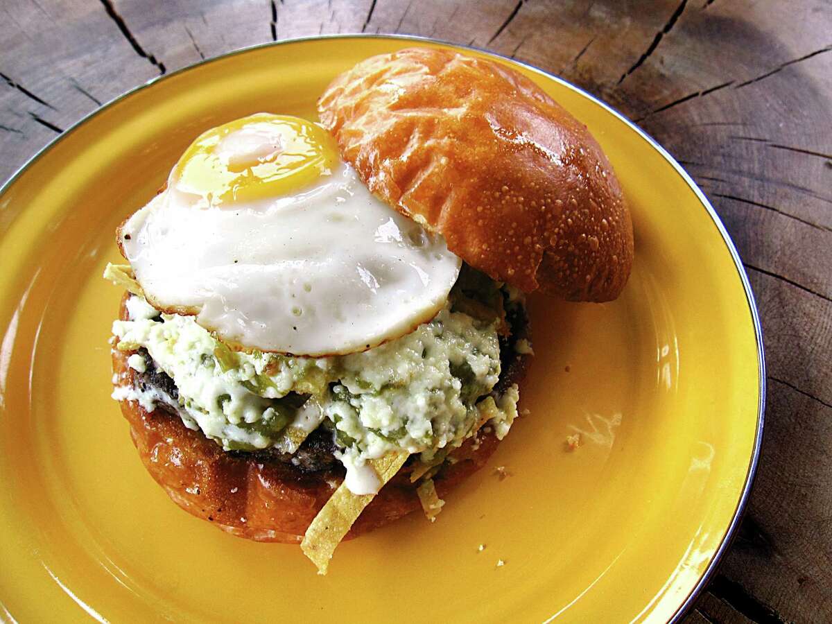 A chilaquiles burger with tortilla chip strips, salsa verde, crema, queso fresco, black beans and a fried egg from Burgerteca.