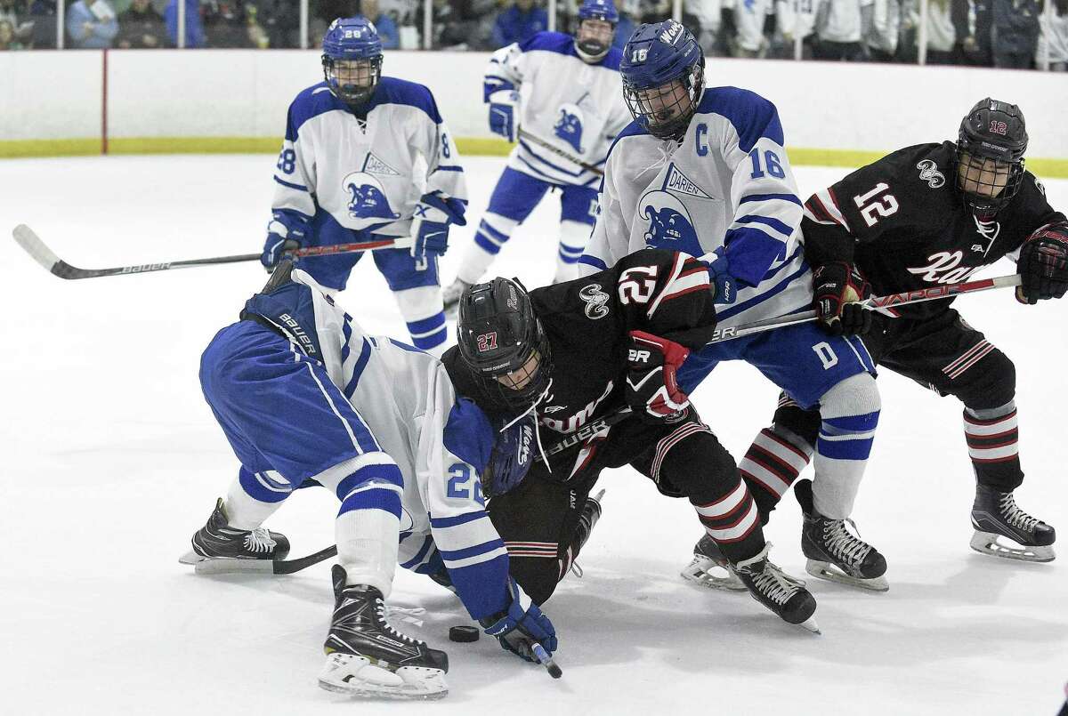 Darien Bennett McDermott (22) and New Canaan Sam Augustine (27) face off during a FCIAC boys ice hockey game at the Darien Ice Rink in Darein, Conn. on Saturday, Dec. 23, 2017. Darien defeated New Canaan 8-1.