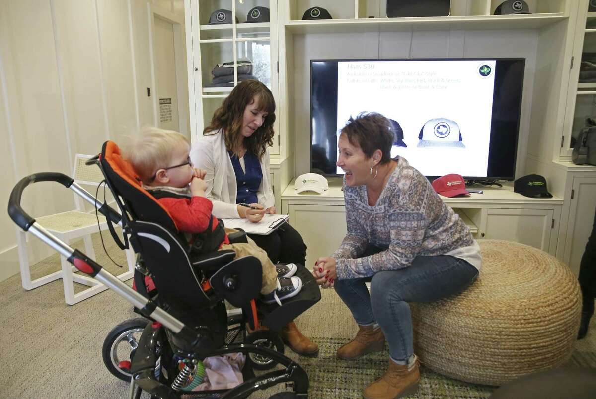 Two-year-old Oscar Wilkens is entertained by Terri Carriker, right, as his mother, Christy Wilkens fills out forms at Compassionate Cultivation in Manchaca, Texas facility, Thursday, Feb. 8, 2018. The boy suffers from epilepsy will use cannabidiol in order to alleviate the symptoms of the brain disorder. The Wilkens were one of the first customers of Compassionate Cultivation on their first day of dispensing the medication.
