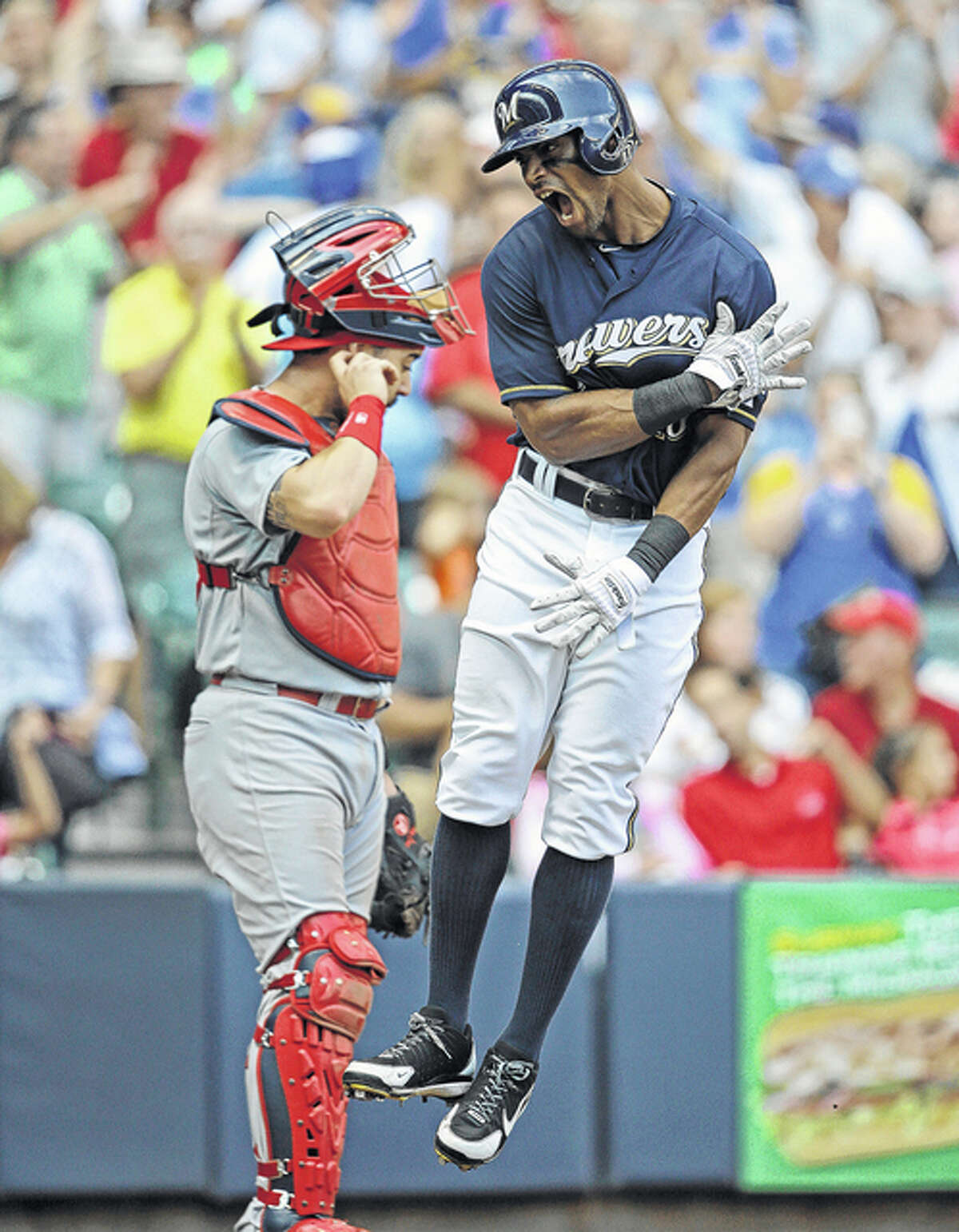 The Brewers’ Khris Davis (right) crosses the plate after his two-run home run while Cardinals catcher Tony Cruz looks on in the eighth inning Sunday in Milwaukee.