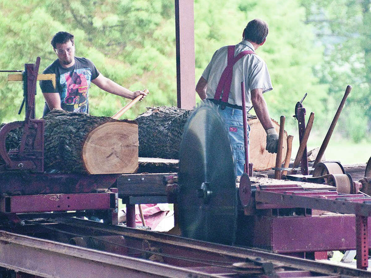 Kuehn-Ziegler Sawmill workers, based in Neillsville, Wis., saw logs as part of the hands-on attraction that people watched during the silver anniversary of the Tri-County Antique Club’s Olden Days Festival in Dow.