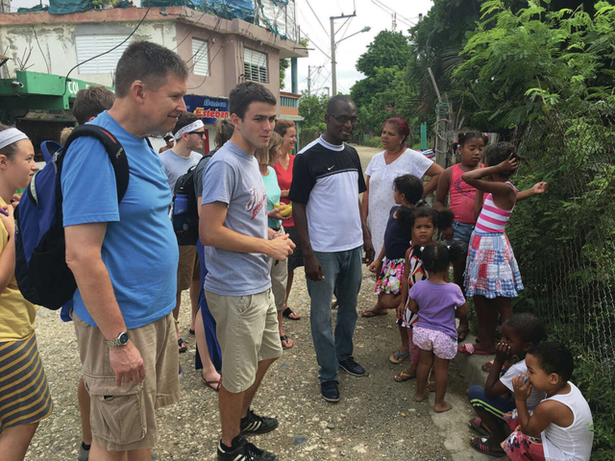 Tim Quigg (from left) and Mason Pohlman, both of Jacksonville, and a Haitian pastor talk with people in Pontezuela, Dominican Republic, during a mission trip organized by Lincoln Avenue Baptist Church.