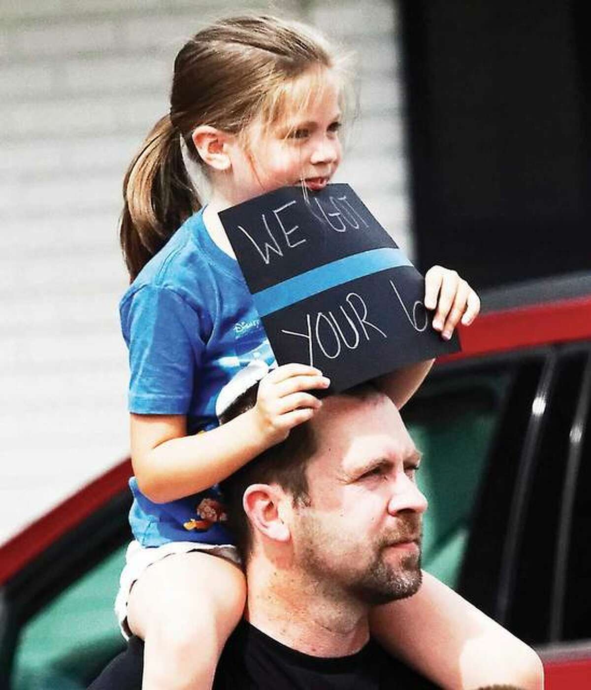 Isabella Hewitt perches on the shoulders of her father, Jason Hewitt, of Jerseyville, Sunday to watch the homecoming convoy of Jerseyville police officer Nathan Miller. She held a small sign reading “We got your 6.”