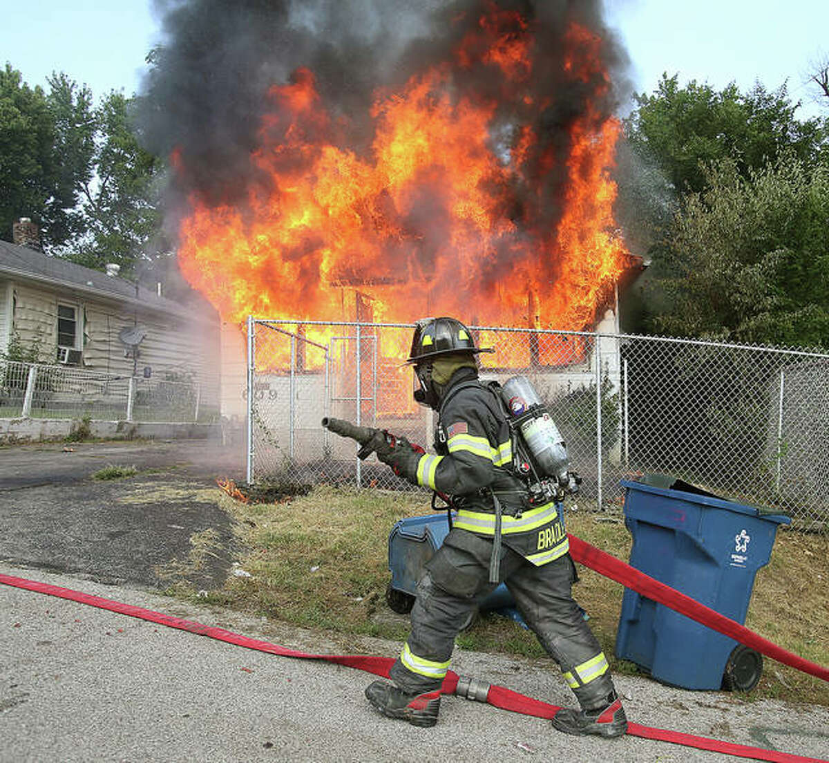 An Alton firefighter pulls a hose into position Tuesday outside 609 Marsh Avenue as flames engulf the front of the house with a young girl still trapped in the basement. It was a tense 10 minutes as firefighters worked to extinguish the fire, reach the girl and police having to restrain family members who wanted to go back in to save her. About 10 minutes into the fire the girl was rescued, virtually uninjured, by Alton firefighters.