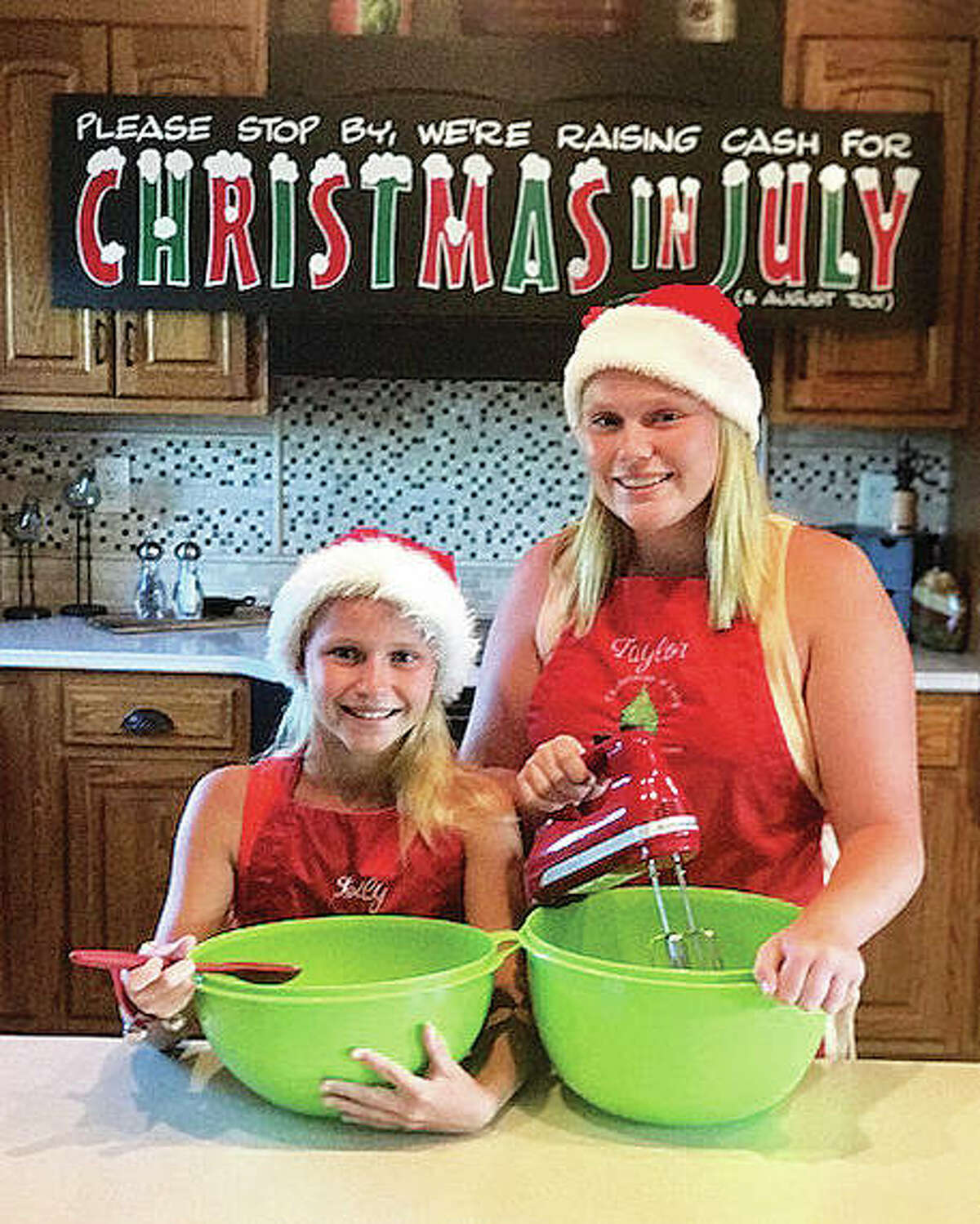 Taylor,13, and Lily Freer, 10, started the annual Christmas in July in 2009. Today, they continue hosting the event at their family business, Freer Auto Body, and are pictured while practicing making their “MawMaw” Margaret Freer’s cheesecake to serve Friday at this year’s event.