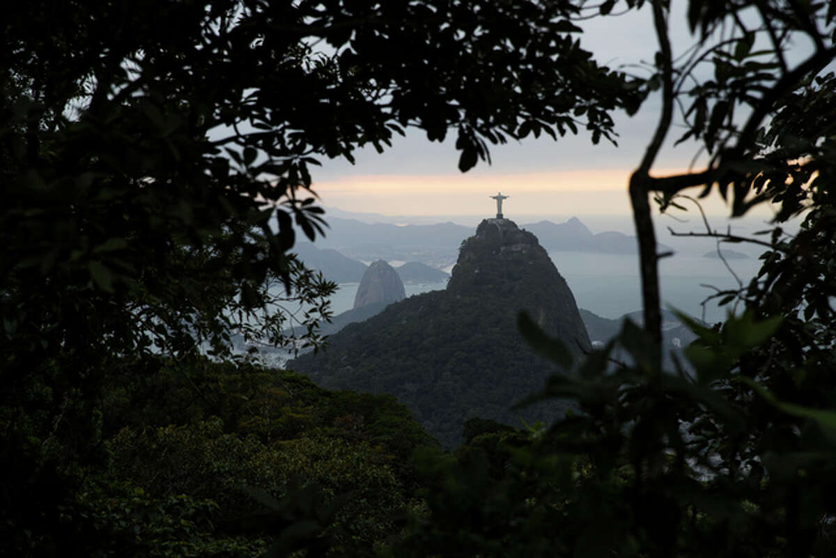 The Christ the Redeemer statue and Sugar Loaf mountain are pictured between trees as the sun rises in Rio de Janeiro, Brazil, Thursday, Aug. 4, 2016. The 2016 Summer Olympics is scheduled to open Aug. 5. (AP Photo/Felipe Dana)