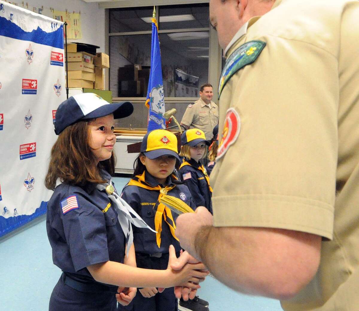 New Cub Scout Addie Healy, left, shakes hands during her Boy Scouts of America, Greenwich Council, Pack 23 of North Mianus, induction ceremony at North Mianus School in Greenwich, Conn., Thursday night, Feb. 8, 2018.