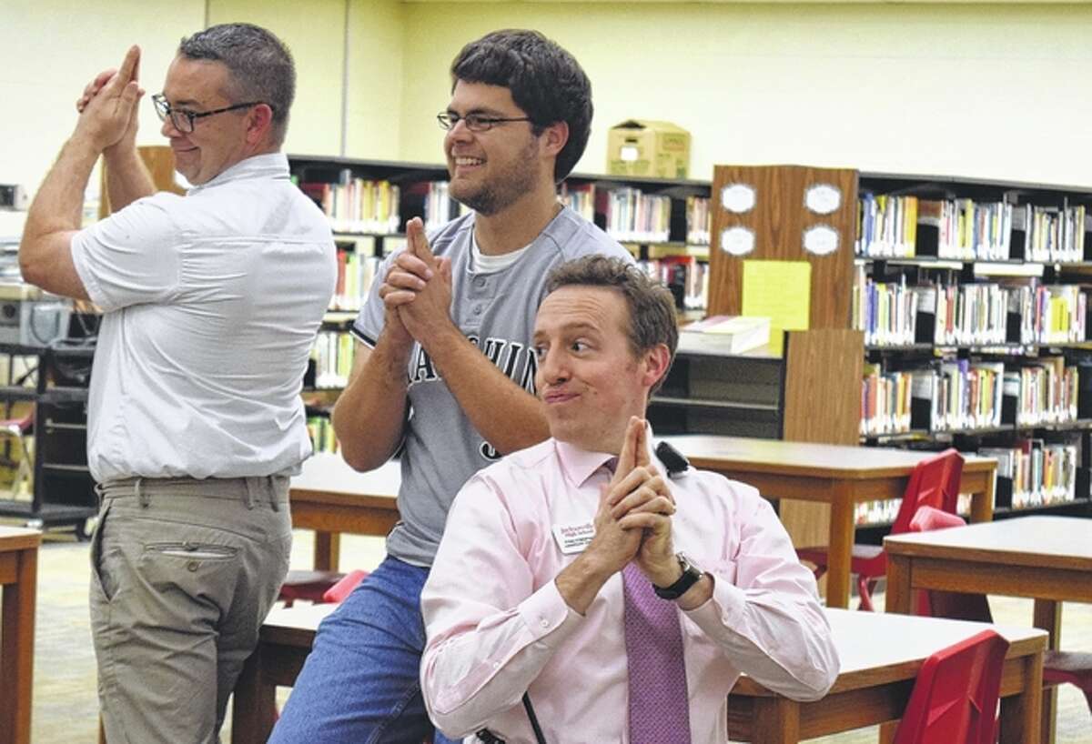 Scott March (from left), Nate Paulus and Tim Chipman strike a pose from the television show “Charlie’s Angels” during the Something on Thursday Afternoons program at Jacksonville High School. Teachers and staff members meet every other week to trade ideas and hear about professional development opportunities.