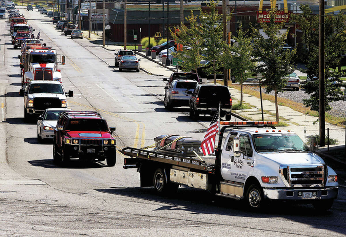 The casket of Richard “Dick” Klaffer, owner of Bill and Joe’s Towing, rides on a flatbed truck followed by tow truck operators during a funeral procession in Alton. Klaffer, 63, died Sept. 30.