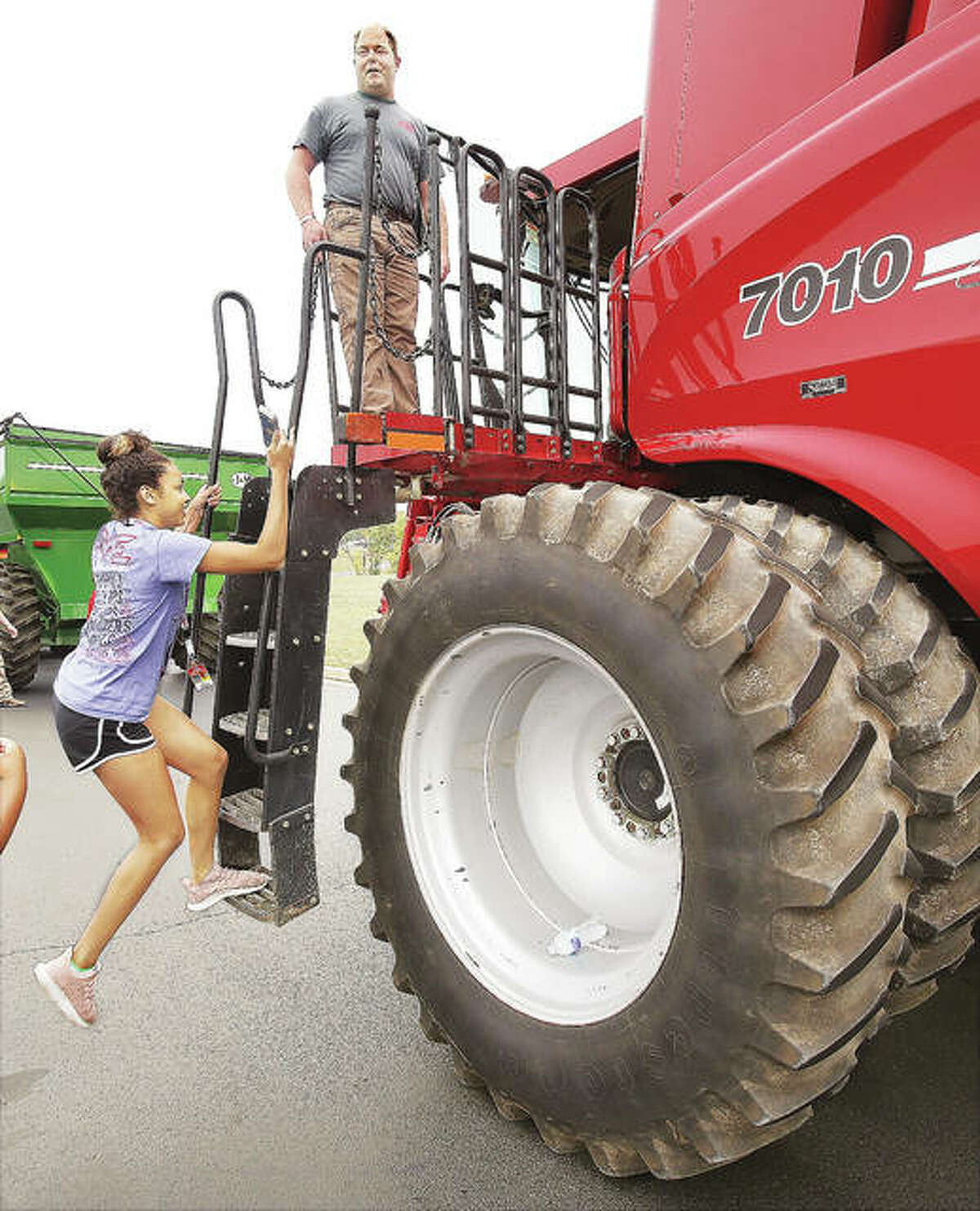 An Alton High School student makes her way up the ladder to a farm combine Wednesday operated by Nick Koeller, above, from Koeller Bros. Inc. farms in Godfrey, during a hands-on lesson for students about farm implement safety and driving. Various students in agricultural and driver’s education classes learned about the equipment and the visibility limitation of drivers on the road. Students were particularly shown blind spots and turn signal systems during their tours of three large farm implements.