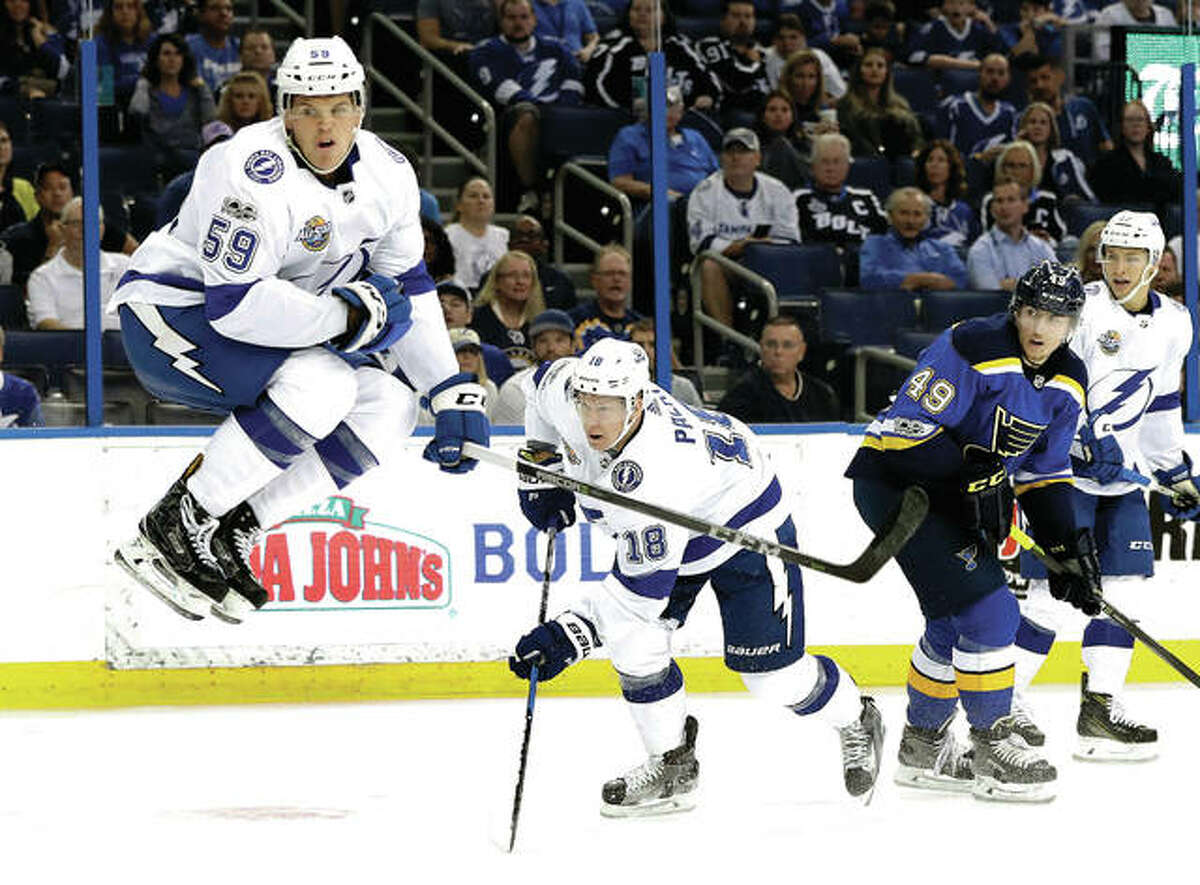 Tampa Bay Lightning defenseman Jake Dotchin (59) leaps out of the way after left wing Ondrej Palat (18) got off a shot after battling with Blues center Ivan Barbashev (49) during the second period of Saturday’s game in Tampa, Fla.