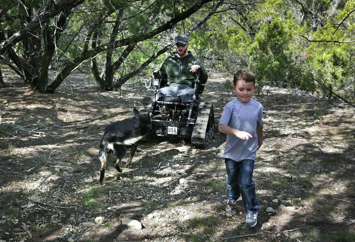 Luke Cifka, a retired Army staff sergeant who lost both legs above the knee in a bomb blast in Afghanistan in 2013, explores the woods behind his house in Canyon Lake with his son, Wyatt, and service dog, Hera. Cifka returned to Afghanistan in December with the charity program Operation Proper Exit.