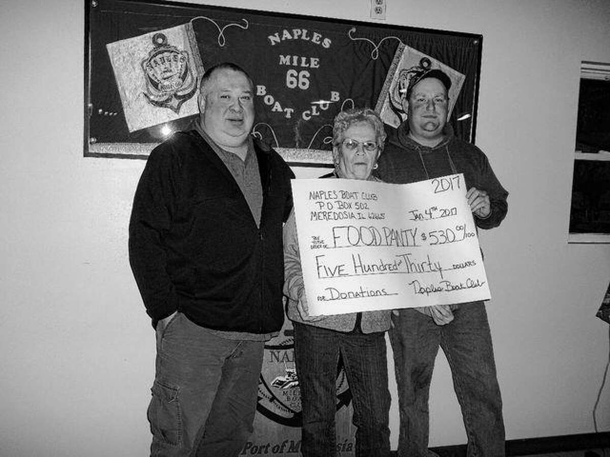 Meredosia Food Pantry volunteers Donnie Whewell (from left) and Carol Ruyle receive a check for $530 from Naples Boat Club member Brent Hinners.