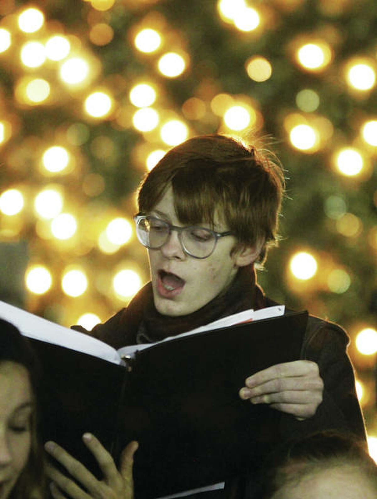 Austin Turnbull, a member of the Alton High School Chamber Singers, sings Christmas carols during the 23rd annual Christmas Tree Lighting in Lincoln-Douglas Square in downtown Alton. The ceremony drew about 250 people, and is sponsored by Alton Main Street.