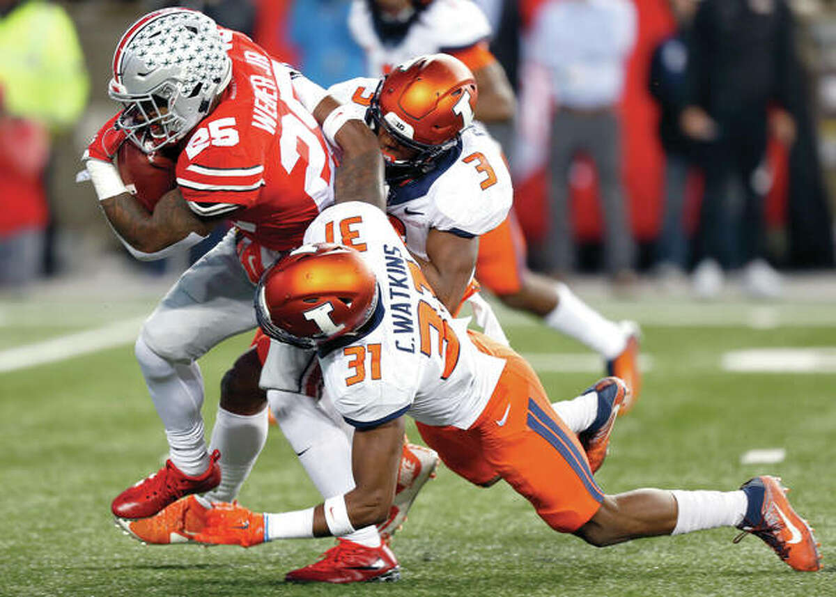 Ohio State running back Mike Weber, left, drags Illinois defenders Del’Shawn Phillips, right, and Cameron Watkins during Saturday’s Big Ten game in Columbus, Ohio.