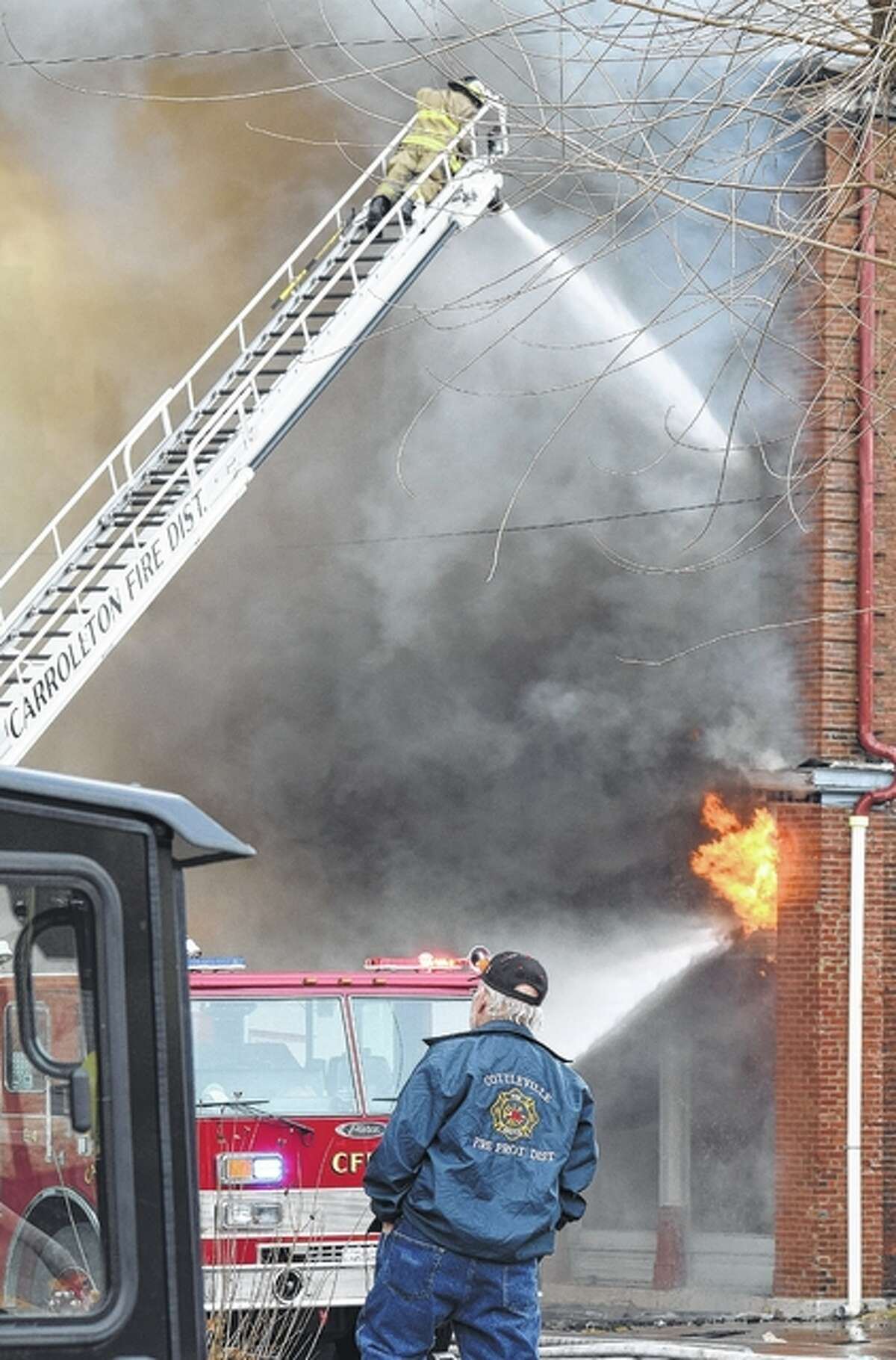 A Carrollton firefighter works to contain a fire that destroyed three buildings on North Main Street in White Hall.