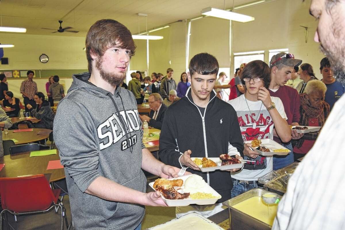 Lafayette Academy students Coby Timmons (from left), Ronald Miller and Andrew Hart go through the food line Friday at the school’s annual Soul Food Dinner.
