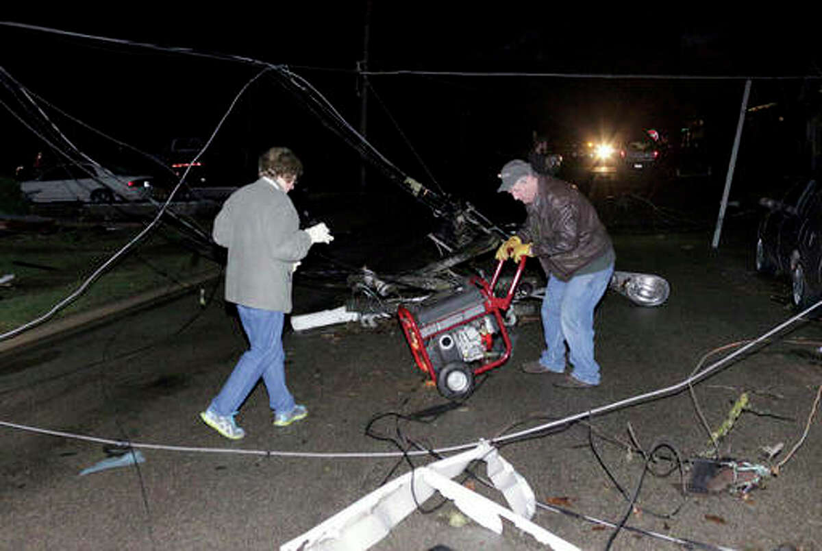 Chris Yucus | News Tribune (AP) A man and woman try to wheel a portable generator through downed wires after a storm moved through Naplate on Tuesday. Tornadoes touched down in the upper Midwest on Tuesday.