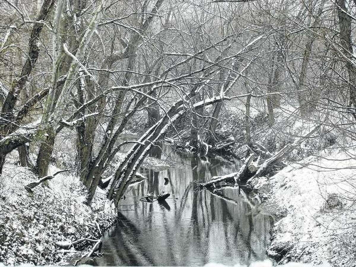 A snow-shrouded creek looks calm but serves as a reminder that winter is not yet over. Snow that moved into west-central Illinois early this week has largely melted, but it is being followed by bitterly cold temperatures.