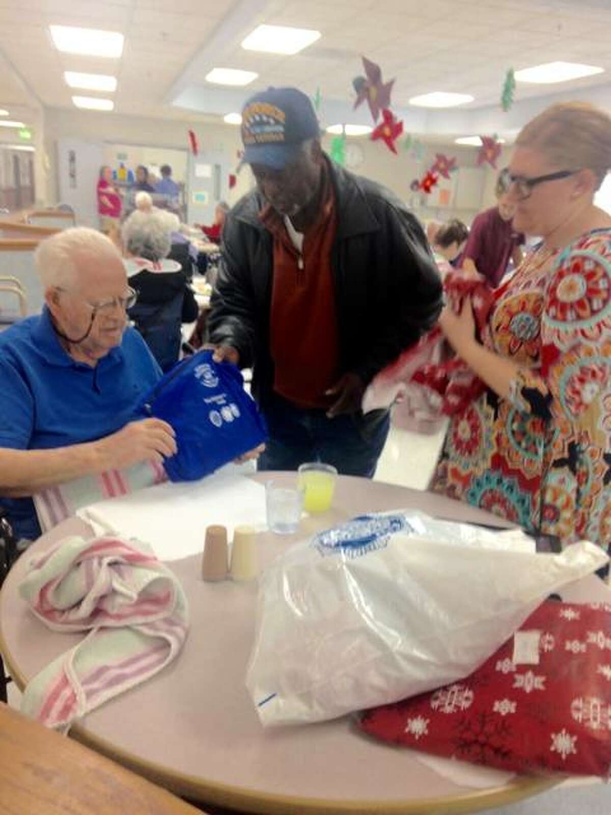 Clifford Barnes, 91, opens a gift containing several items in a bag from Joe Brice, commander of Allen Bevenue American Legion Post 354 of Alton, at Rosewood Care Center. Brice brought Christmas gifts to 18 veterans at the long-term care facility, and 100 presents overall to residents of five area nursing homes. Activities Director Frances Allen, right, assisted some of the men in opening their presents. Linda N. Weller/The Telegraph