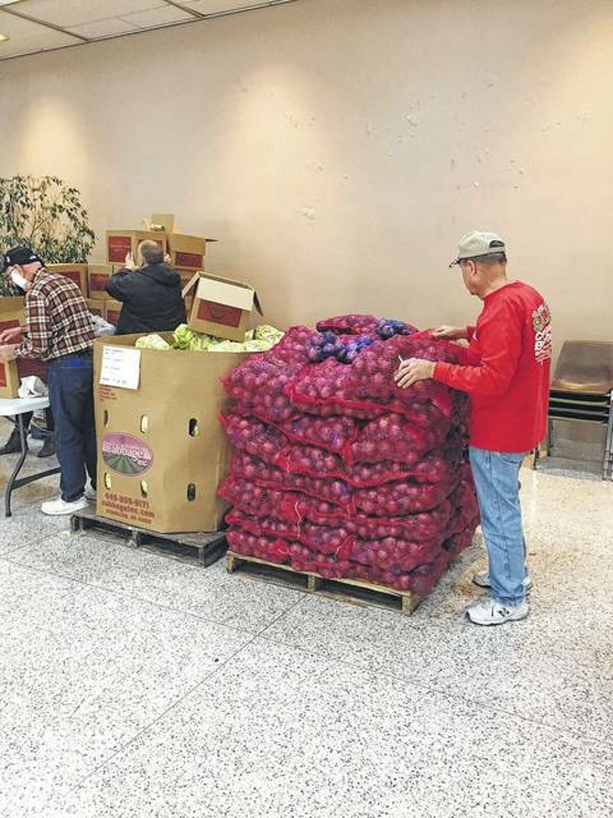 Volunteers help sort loads of potatoes, cabbage and other food items.