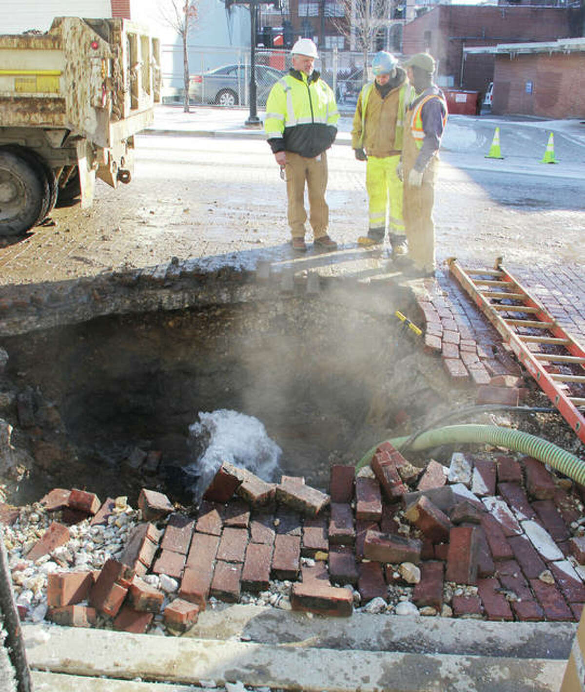 Superintendent Doug Wagner, left, subforeman Mark Harris and worker Jeff Nichols, all of Illinois American Water, talk about how best to deal with the crack of a 12-inch water main at State and Fourth streets in Alton Wednesday morning. Water from the break, one of two large breaks reported in the city late Tuesday and early Wednesday morning, shot water about 30 feet into the air at one point.