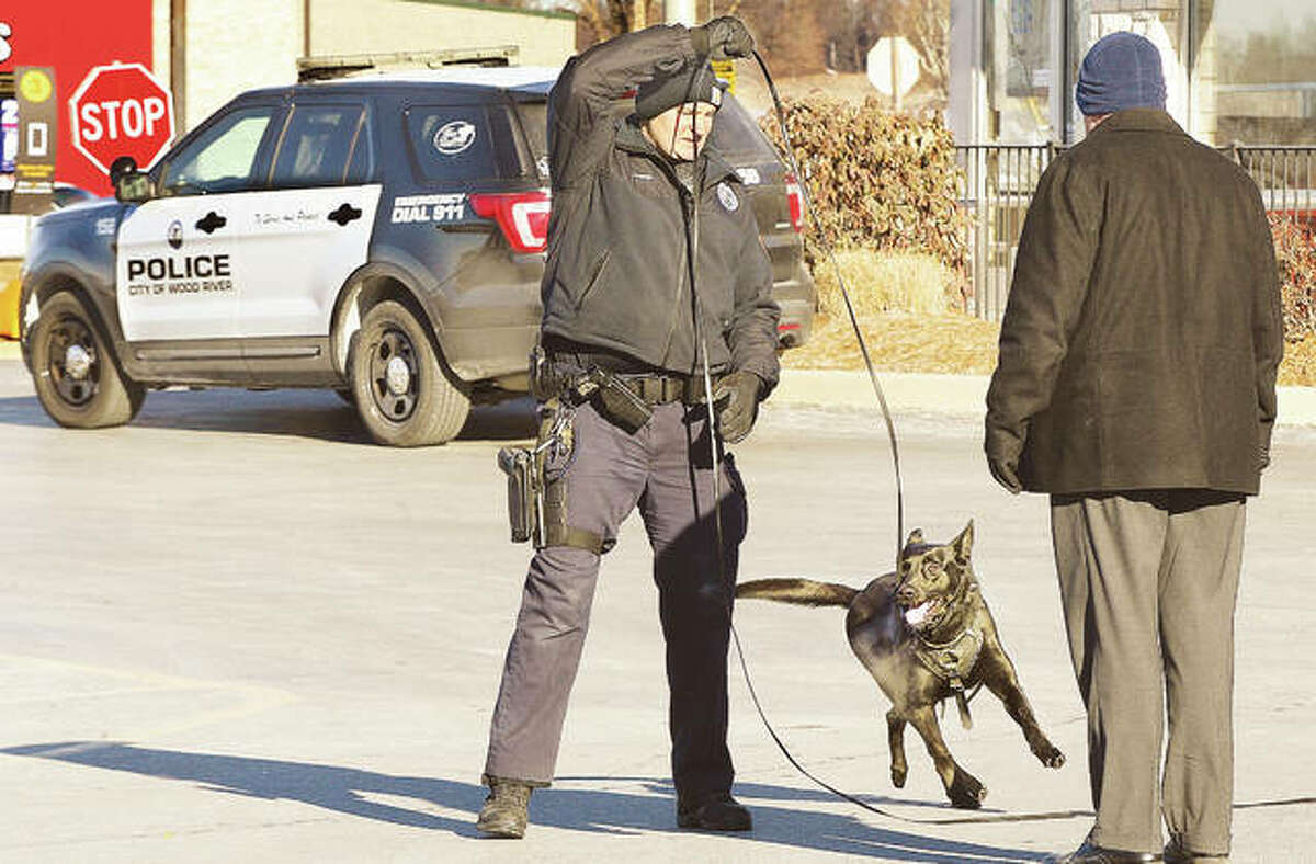 Wood River Police canine officer John Hoefert, and his eager partner, Clark, stop to consult with Deputy Police Chief Dan Bunt, right, while attempting to track a man who robbed the U.S. Bank on Edwardsville Road in Wood River Tuesday morning. The description of the robber matches the one of a man who allegedly robbed banks in Alton, East Alton and Godfrey all in just a little over a month. The methods in all four robberies were similar and the robber of those banks has not been caught.