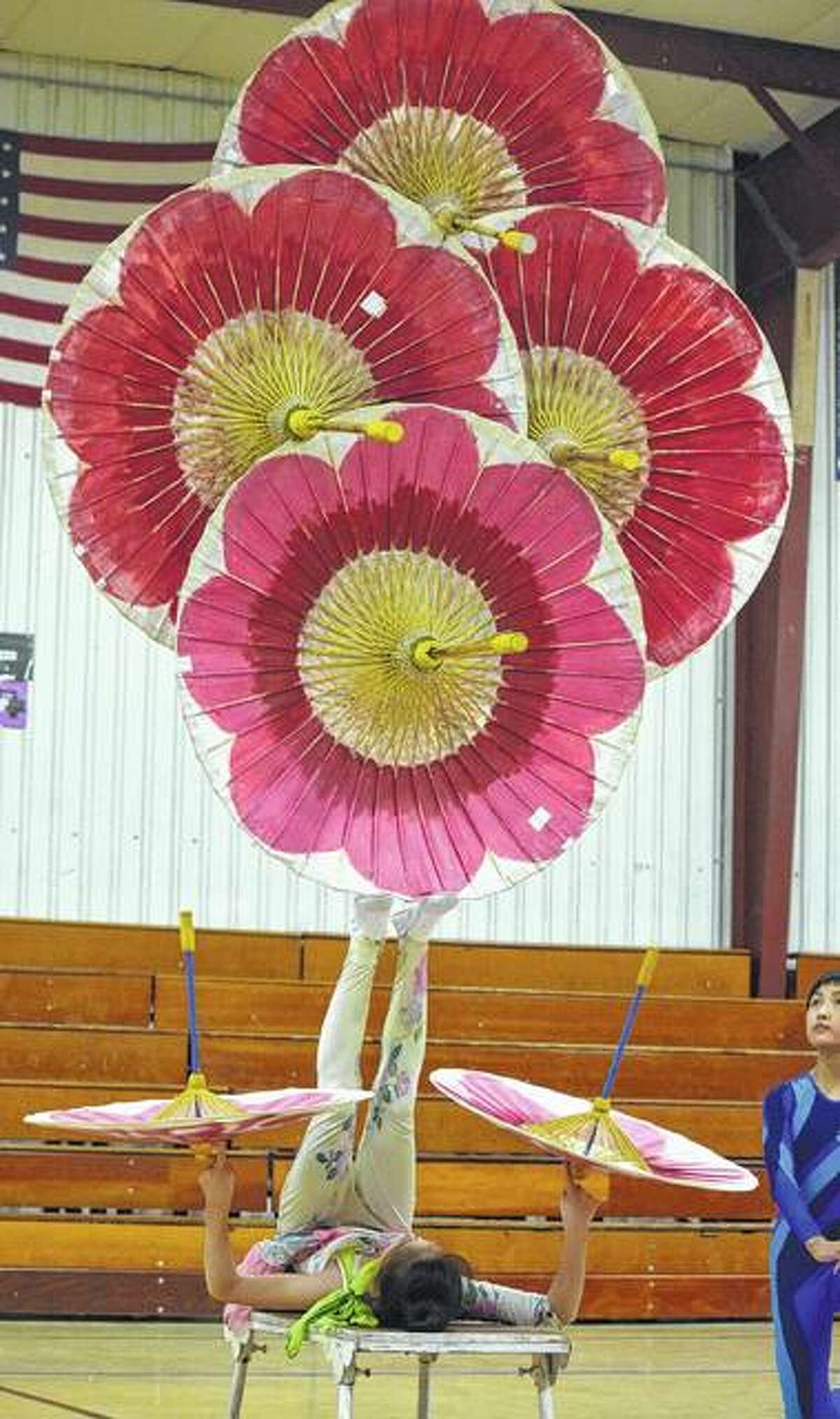 Wang Ling Yue (Ava), 12, a performer with the Fabulous Chinese Acrobats, does a balancing act using Chinese umbrellas Tuesday at North Greene Elementary School.