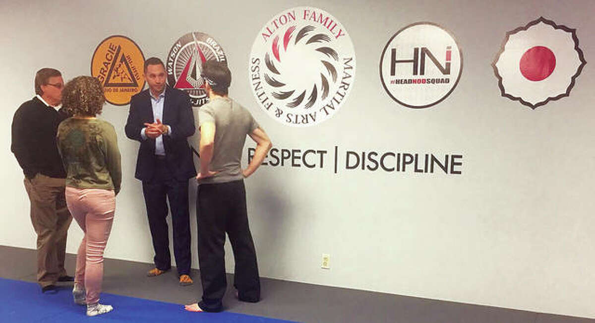 Alton Family Martial Arts and Fitness owner Adam Marburger, second from right, stands in his newly-renovated martial arts studio space, Alton Family Martial Arts and Fitness, located within Nautilus Fitness Center, discussing programs with, from left, Alton Mayor Brant Walker, RiverBend Growth Association’s Trish Holmes and the studio’s lead instructor Cort Wahle.