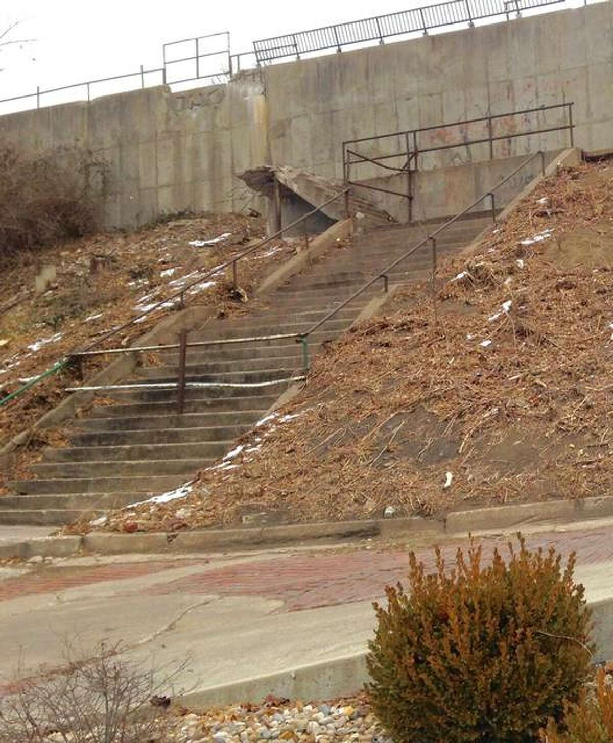 Alton Public Works and Park departments’ workers recently cleared a hill of some plant growth Downtown by Fourth Street, below Market Street, to determine what repairs are needed to a graffiti-defaced wall, staircase that ends mid-air and a sidewalk that runs from the steps to the south.
