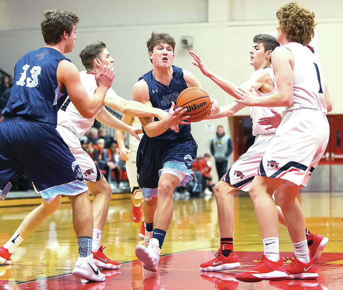Jersey’s Blake Wittman (middle) splits Triad’s defense to drive the lane while teammate Lucas Ross (13) looks on during Friday night’s Mississippi Valley Conference boys basketball game at Triad.