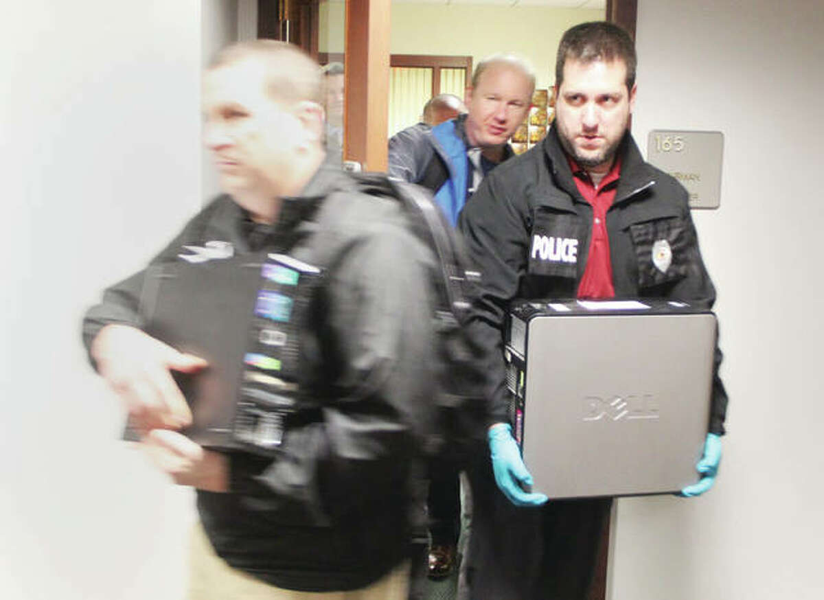 Police officers remove items from the Madison County Board office after serving search warrants Wednesday afternoon. Warrants were also served on the county’s IT office, and the office of Communications Manager Cynthia Ellis. The raid was part of a larger investigation by a newly-formed “Madison County Public Corruption Task Force.”