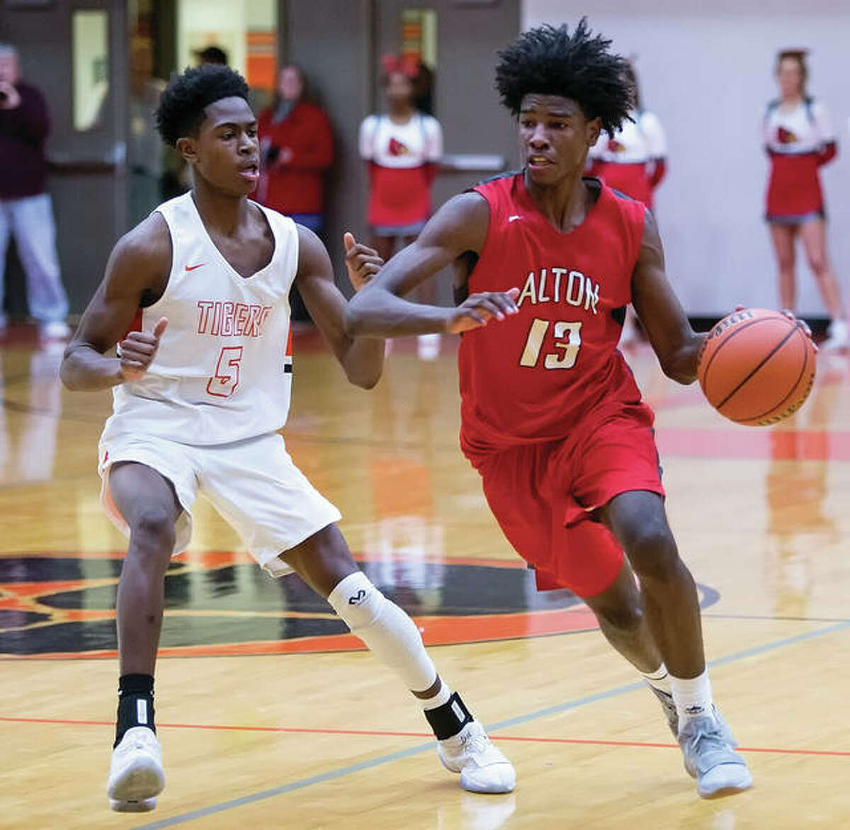 Alton’s Malik Smith (right) dribbles past Edwardsville’s Lavontas Hairston during the first half Friday night in Edwardsville.