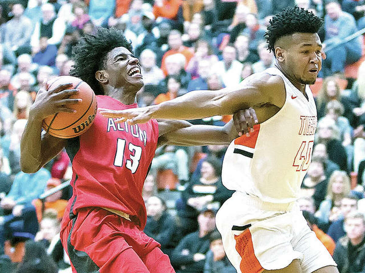 Alton’s Malik Smith (left) fends off Edwardsville’s R.J. Wilson before going up for a shot during a Southwestern Conference boys basketball game Friday night at Lucco-Jackson Gym in Edwardsville. The Redbirds won 55-50 in overtime to halt a four-game losing streak and improve to 10-5.